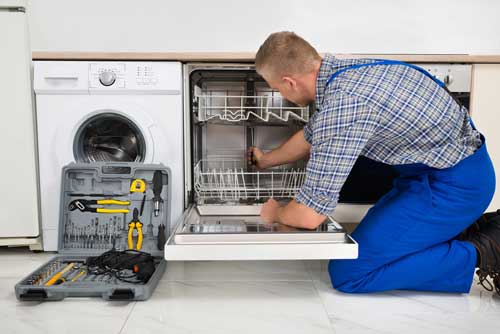 A service provider works on a dishwasher