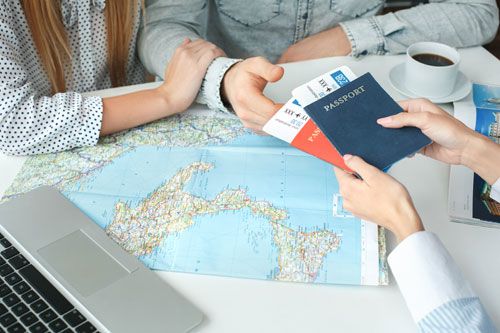 A travel agent hands airline tickets to clients